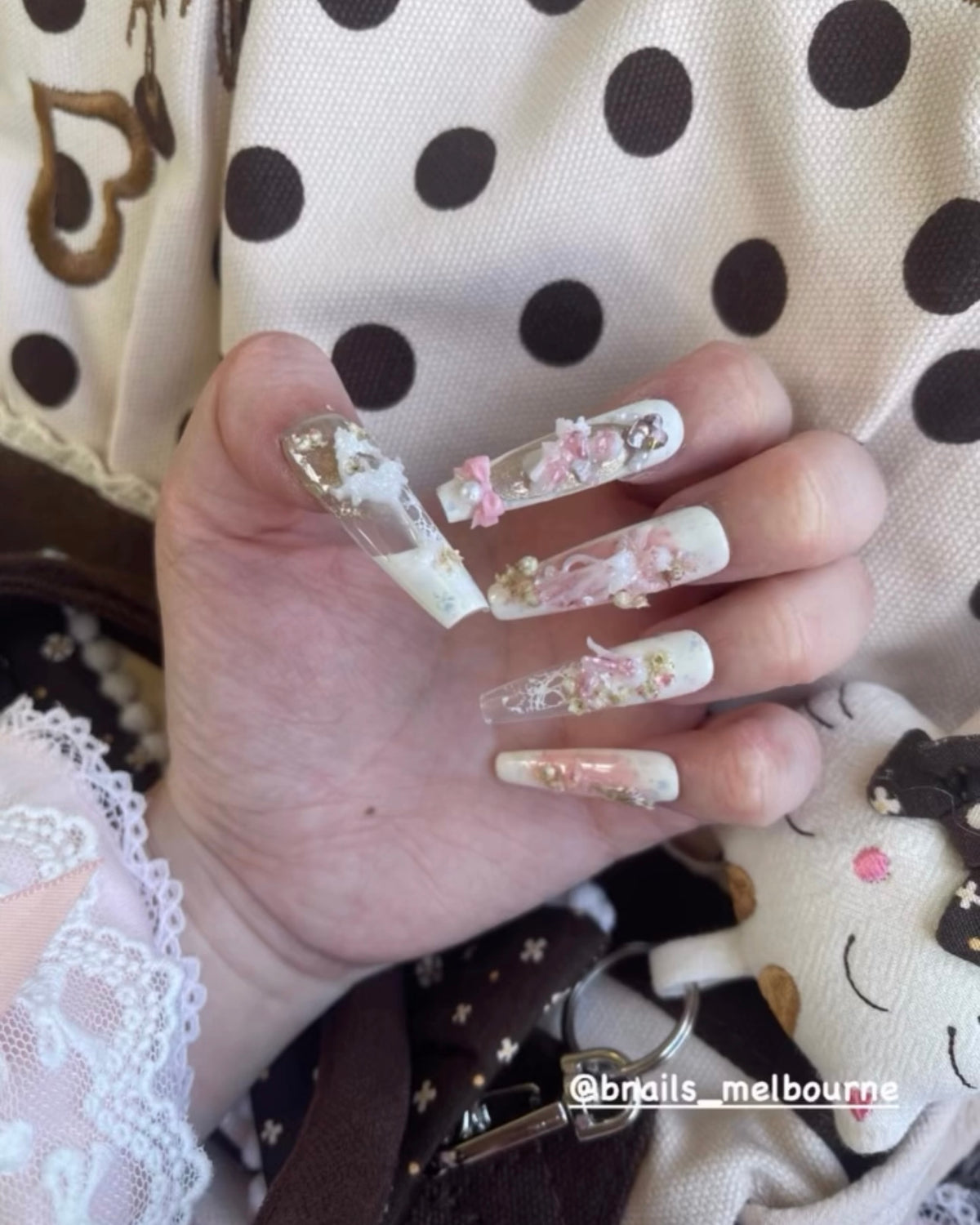 Customer wearing pink and white embellished press-on nails with lace sleeves