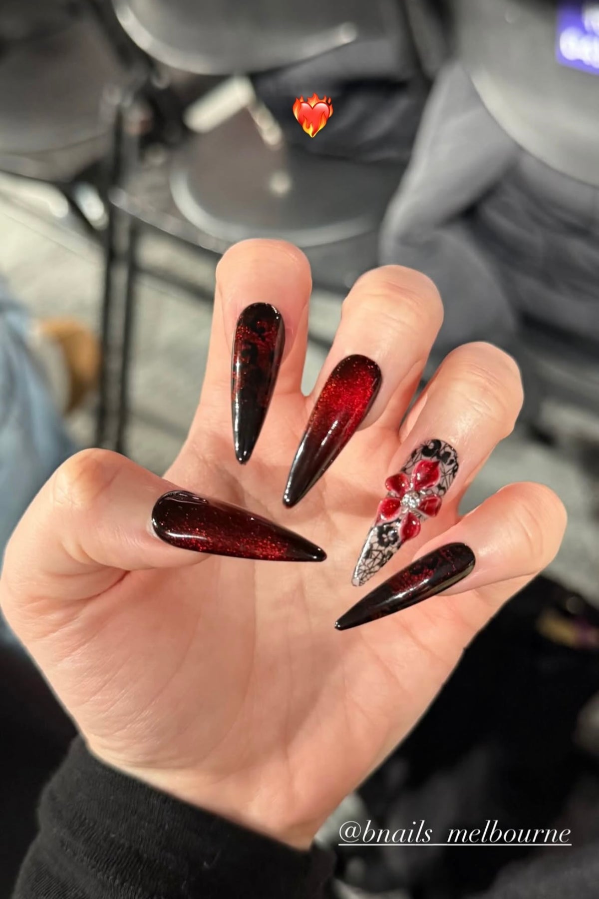 Customer wearing black and red long press-on nails with floral details