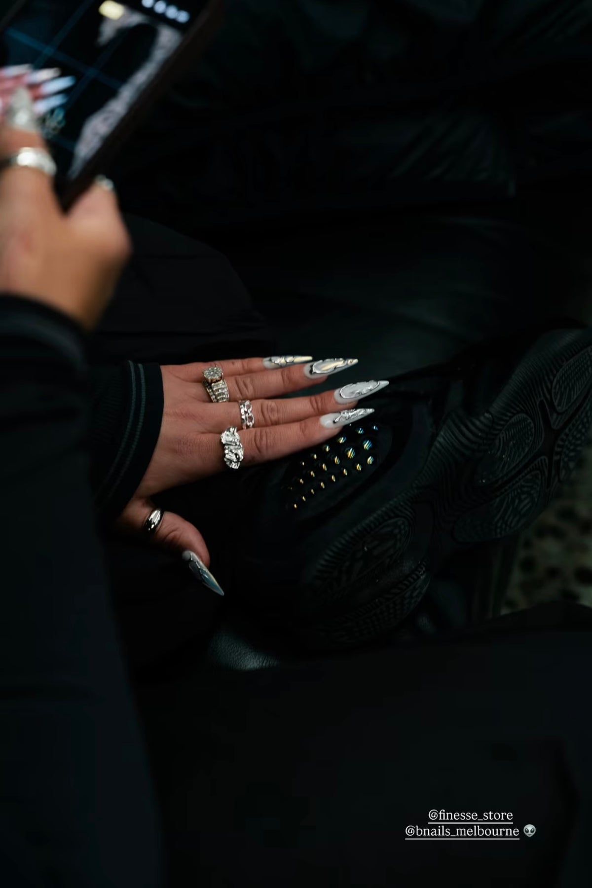 Customer wearing silver and white press-on nails with a dark outfit