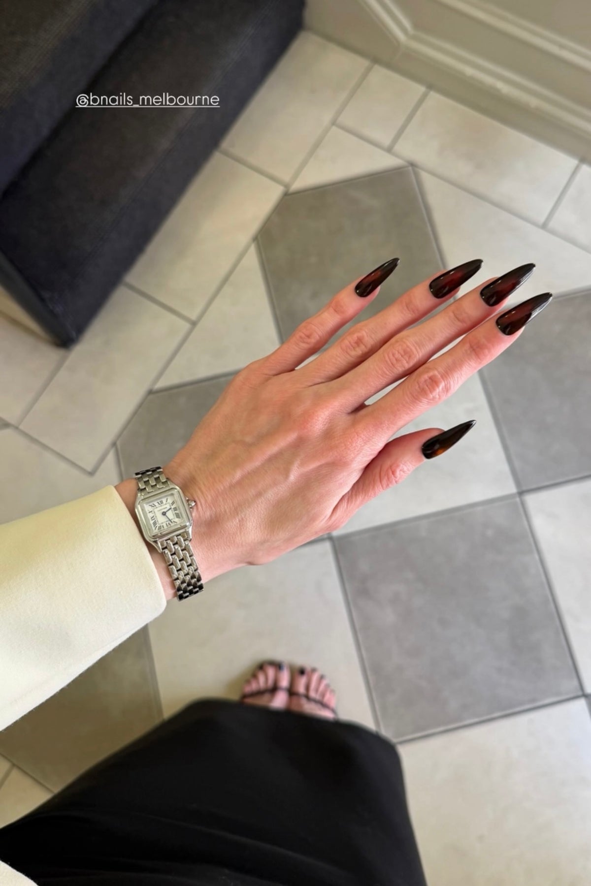 Customer wearing deep red pointed press-on nails with a watch